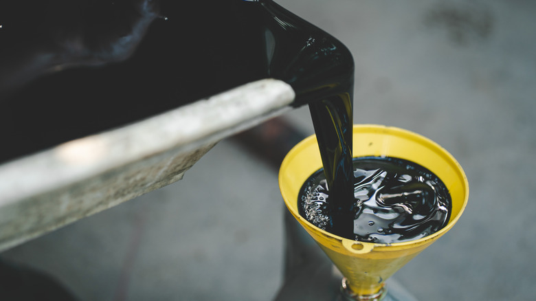 Dirty engine oil being poured into a funnel