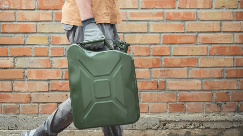 A person carrying a jerry can with oil for disposal