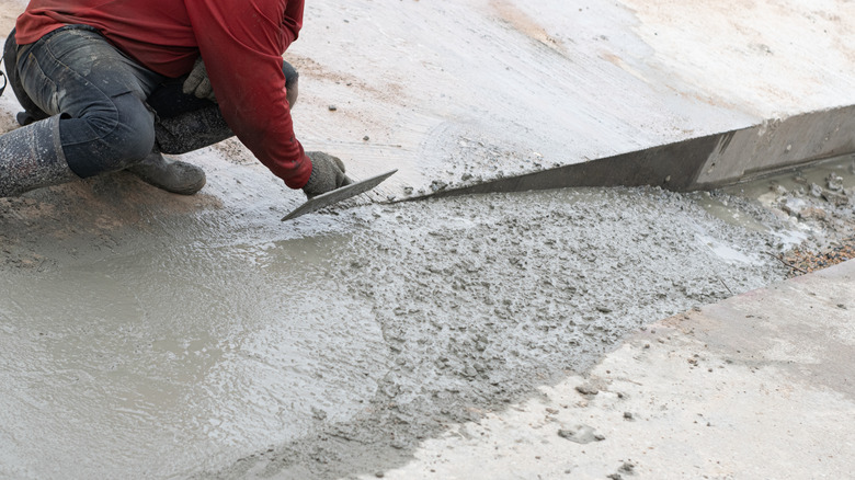 A person leveling a wet concrete floor