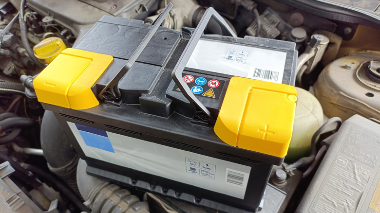 A new car battery on top of the old battery under the hood
