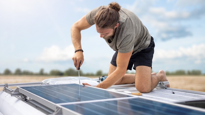 a person installing solar panels on top of van