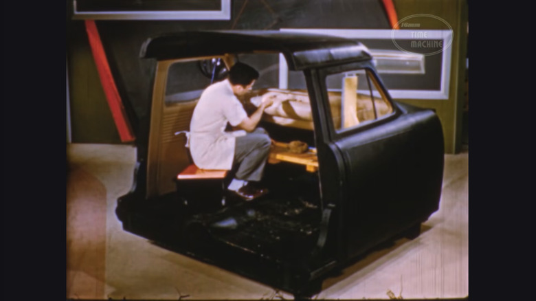 A clay sculptor works meticulously at the clay interior dashboard of a Ford model.