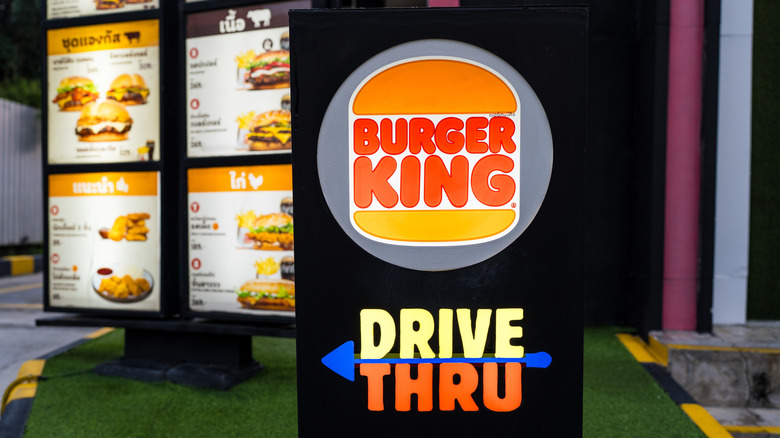 A Burger King drive-thru sign with a menu screen in the background