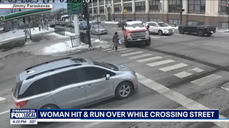 A red truck aims at a woman in a crosswalk