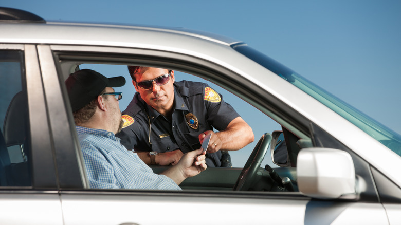 A police officer takes a document from a driver at a traffic stop