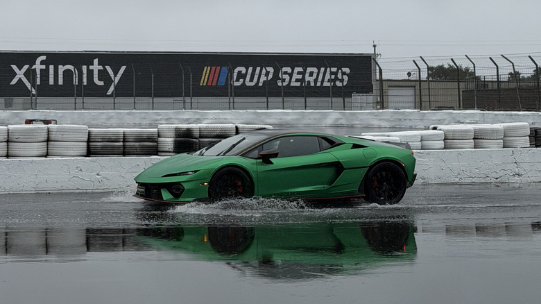 Front 3/4 view of a green Lamborghini Temerario driving on track in the rain