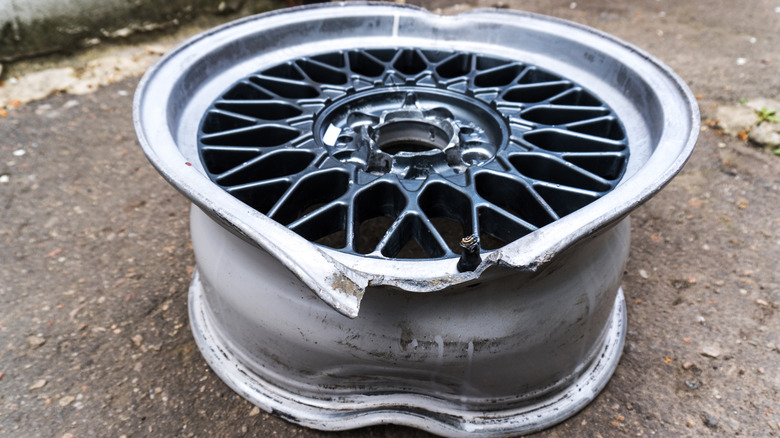 A severely bent and damaged wheel on a sidewalk