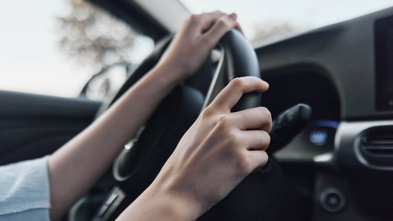 A pereson's hands on car steering wheel