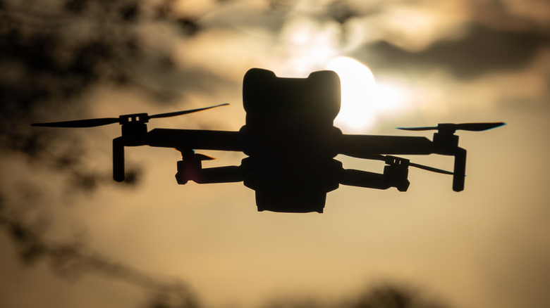 Silhouette of a DJI Mini 5 Pro drone against a setting sun