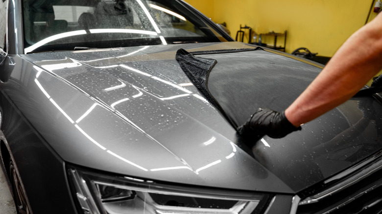 Man using a microfiber towel for drying a gray car