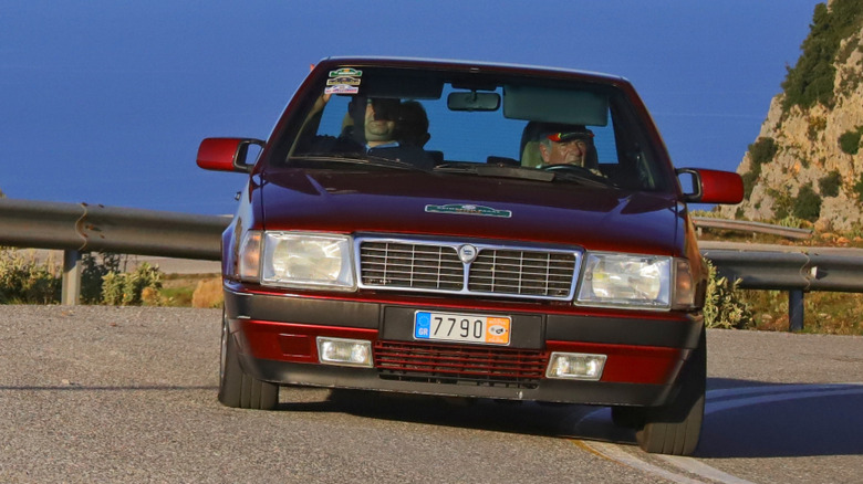 A dark red Lancia Thema 8.32 takes a corner during a hill climb event in Greece