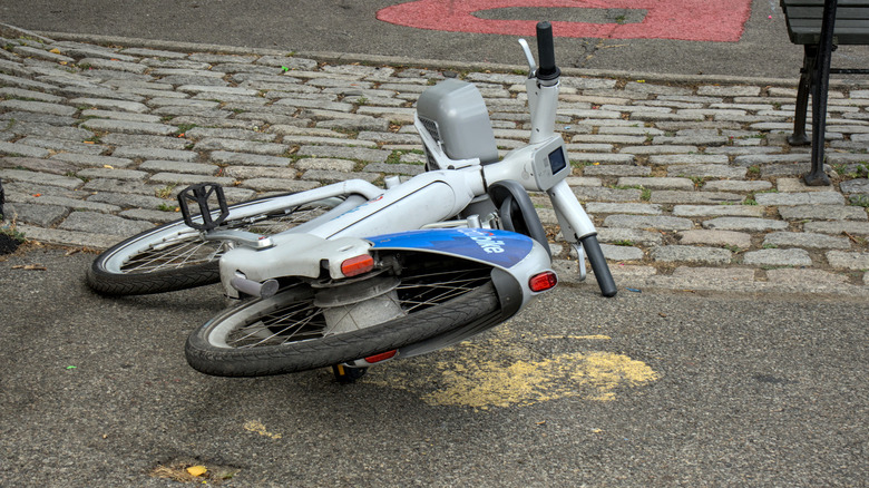 An e-bike laying on its side on the sidewalk potentially following a crash