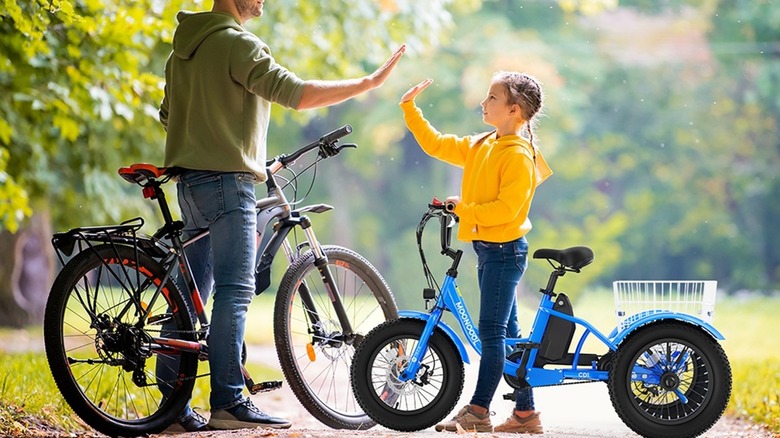 A father and daughter high-fiving on a bike ride, daughter is using an e-bike