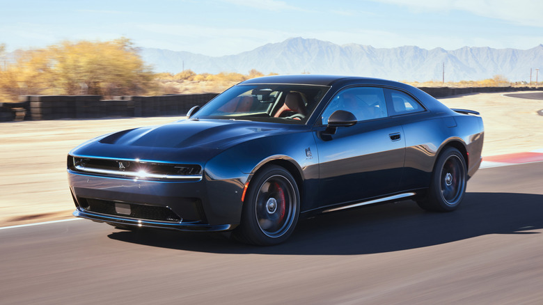 A dark blue 2024 Dodge Charger Daytona EV driving on a desert road.