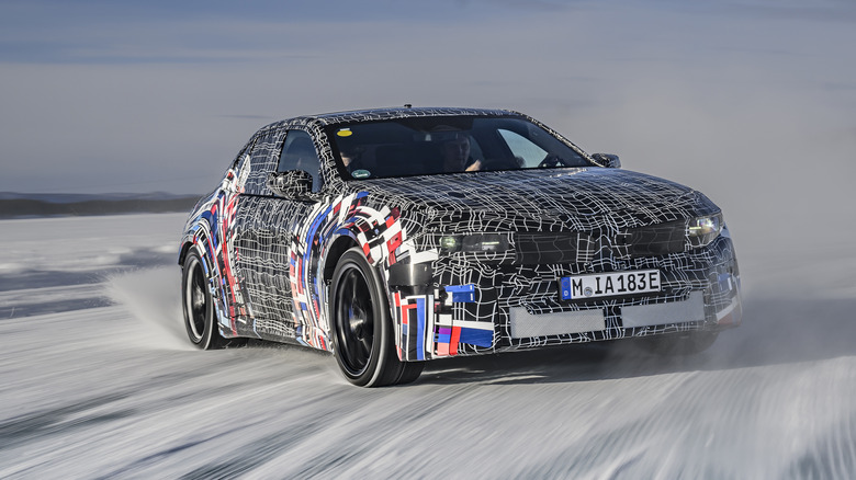 A camouflaged electric BMW M3 drifting in snow