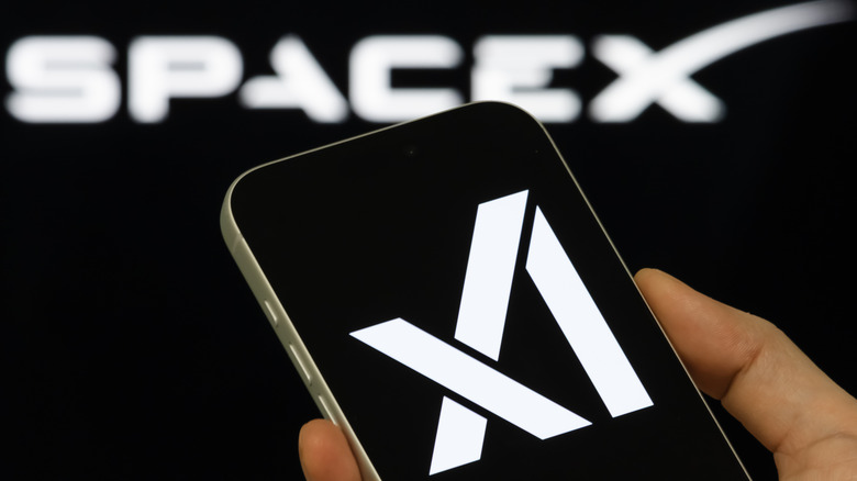 In this photo illustration, a person holds a smartphone displaying the xAI logo, with the SpaceX brand visible in the background, on February 3, 2026, in Chongqing, China.