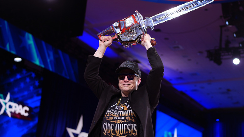 Elon "Chainsaw Man" Musk holding a chainsaw over his head at CPAC this year