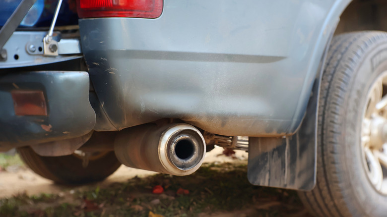 Close-up of a dirty exhaust pipe on a blue pickup truck.