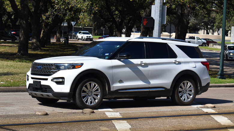 A white Ford Explorer SUV, traveling northbound between a Metro railway tracks and Hermann Park reserve.