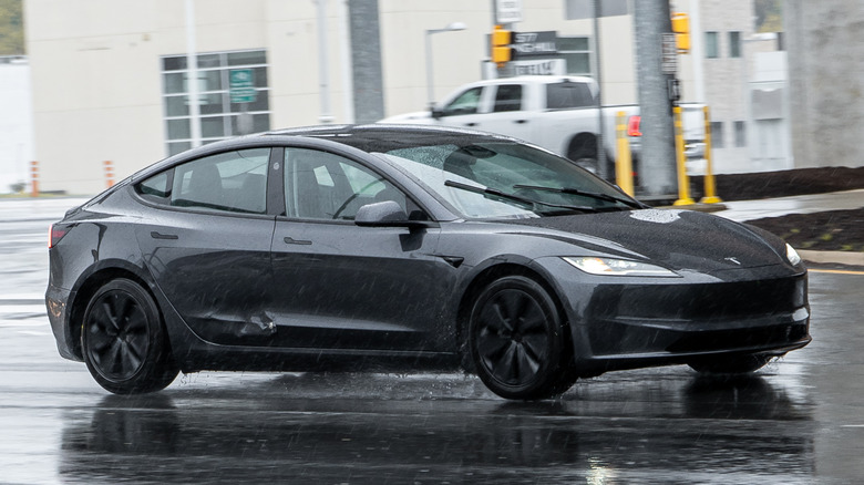 A black Tesla Model 3 driving around Washington DC on a rainy day