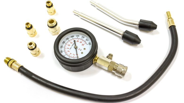 A combustion engine compression test kit, featuring a pressure gauge, hose, and fittings.