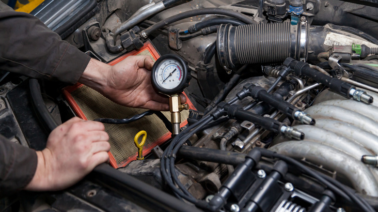 A mechanic preparing to perform a compression test on a vehicle engine.