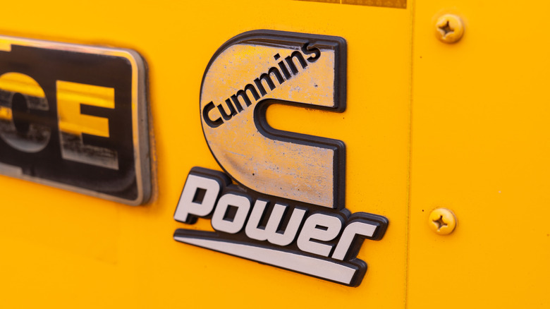 An old Cummins engine badge on a yellow vehicle.