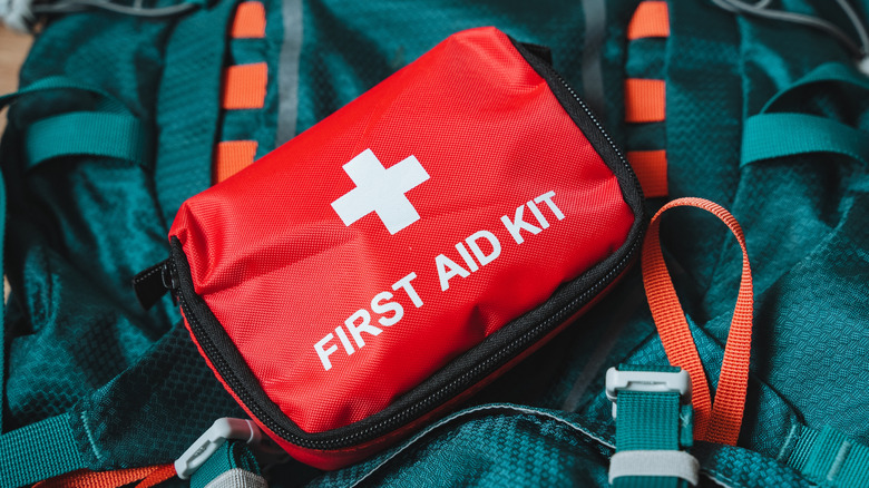 A red first aid kit is shown in close-up.