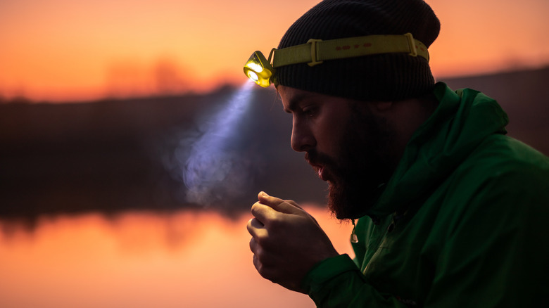 A man wears a headlamp that casts a light beam forward.