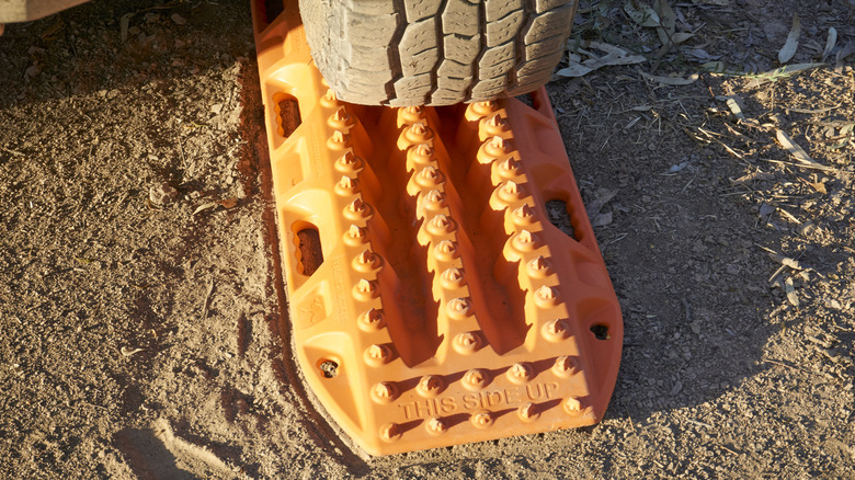 An orange recovery track sits under a tire.