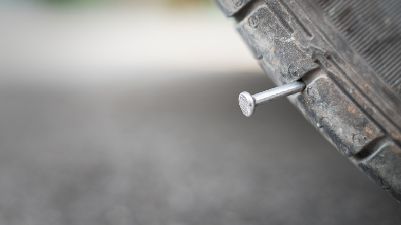 Closeup of a nail puncturing a car tire.