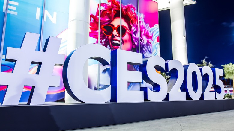 A CES 2025 sign with a vibrant picture of a woman in pinks, reds and purples in the background