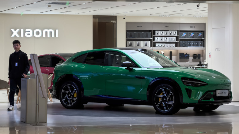 CHONGQING, CHINA DECEMBER 18: A Xiaomi electric vehicle is displayed inside a Xiaomi store at a shopping mall on December 18, 2025, in Chongqing, China, as a staff member stands nearby. Xiaomi has been expanding its presence in the electric vehicle sector alongside its core consumer electronics business as Chinese technology companies move further into the competitive EV market.
