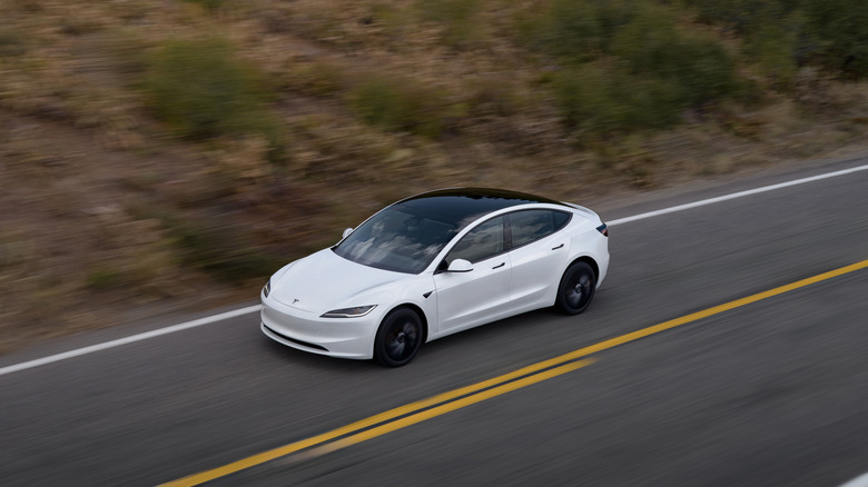 A white Tesla Model 3 traveling on a road