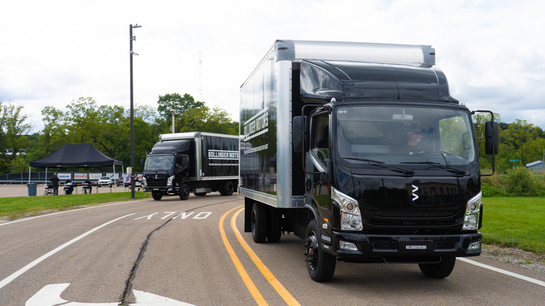 Two Bollinger container trucks connected a road