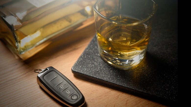 Car key fob lying next to a bottle of liquor and a whiskey glass