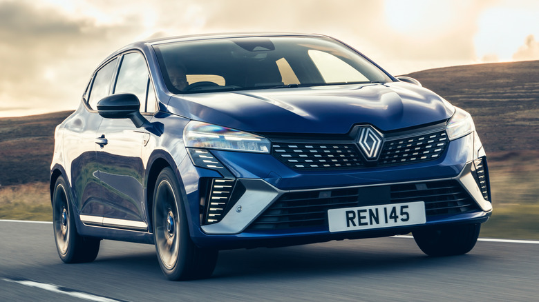 Front 7/8 Blue 2025 Renault Clio on road with sunlit clouds in background