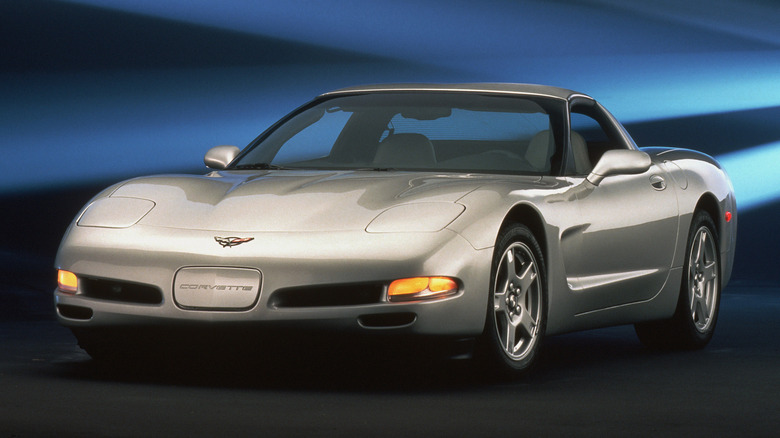 Front three-quarter product shot of a silver 1997 Corvette in front of a blue and grey background.