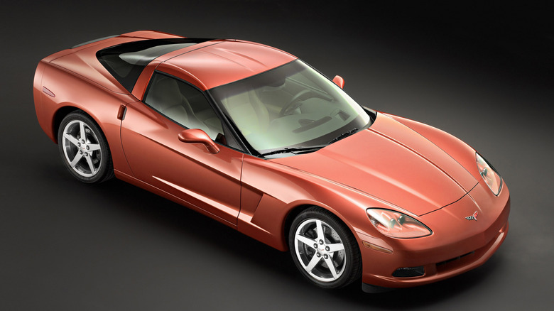 Front three-quarter press shot of an orange 2005 Corvette hardtop against a grey background.