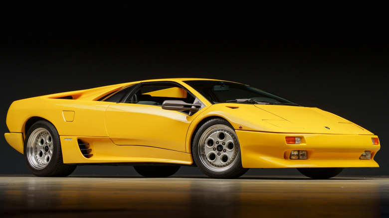 A yellow 1993 Lamborghini Diablo on a reflective floor in front of a black backdrop
