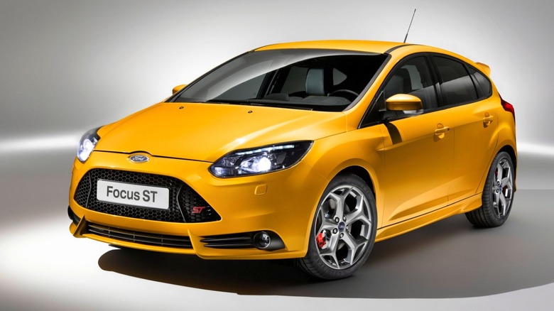 A yellow 2013 Ford Focus ST hatchback in a studio