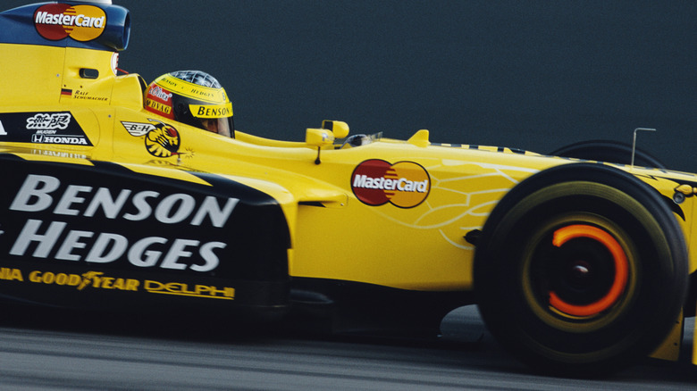 Front disc brake of an older generation F1 car glowing red hot under braking.