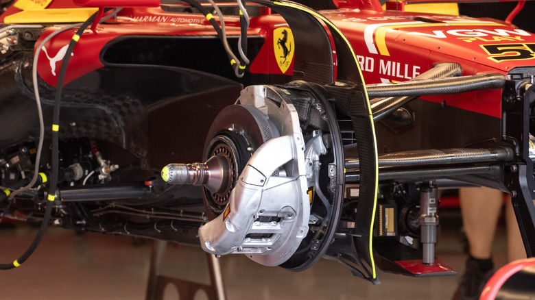 An exposed front caliper and carbon disc brake of a Ferrari F1 car.
