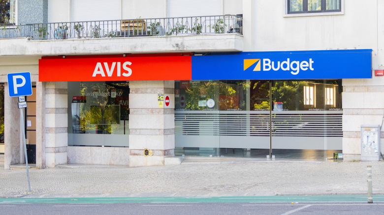 An Avis and Budget rental store with a red AVIS and a blue Budget sign next to each other.