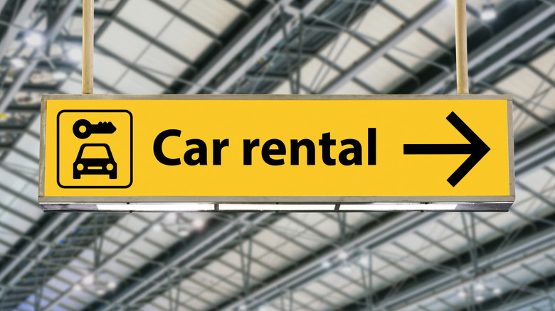 An airport car rental sign with an arrow pointing to the right.