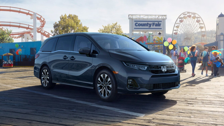 Smoke blue pearl 2026 Honda Odyssey parked in front of a county fair front 3/4 view from waist height