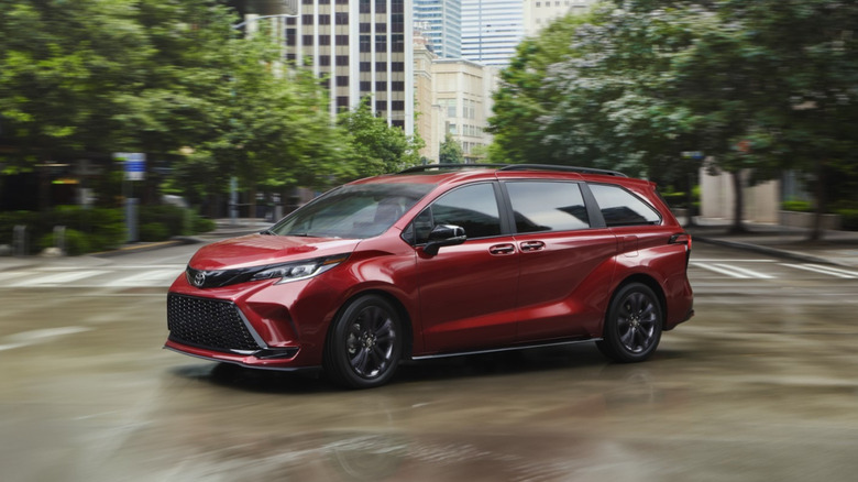 A 2026 Toyota Sienna XSE in Ruby Flare Pearl driving through a modern, blurred city intersection