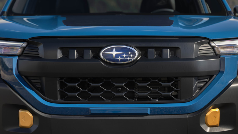 A close up of the front bumper and badge of a blue 2026 Subaru Forester Wilderness