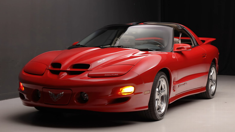 Red fourth-gen Pontiac Firebird on display with t-tops off.