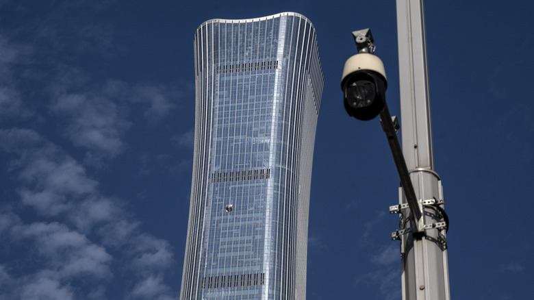 The Citic Tower in Beijing, China, with visible damage after a light aircraft crashed into it, with a security camera in the foreground
